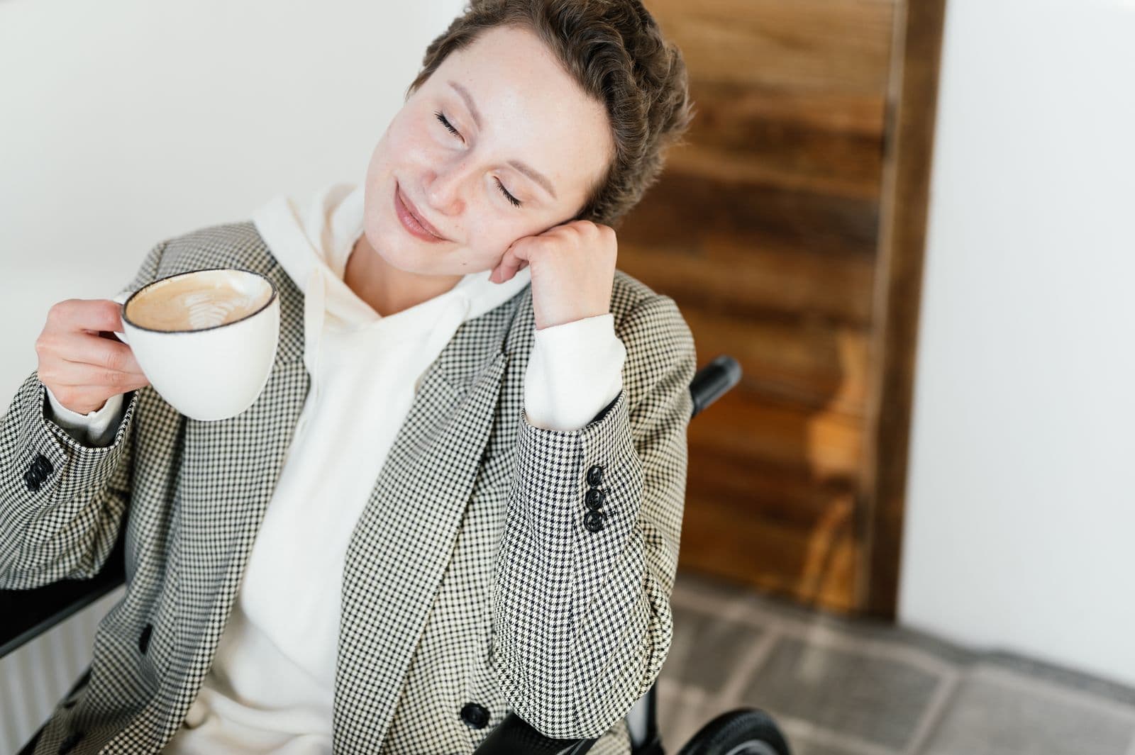 Lächelnde Frau im Rollstuhl genießt entspannt eine Tasse Kaffee